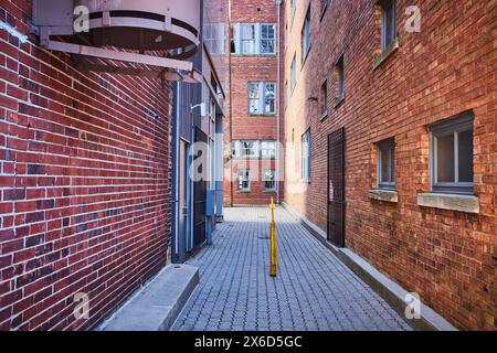 Städtische Gasse mit Feuertreppe und versperrten Fenstern, Blick vom Boden aus Stockfoto