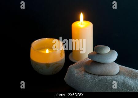 Zwei beleuchtete Kerzen, Handtuch und Steinwaage. Stillleben. Stockfoto