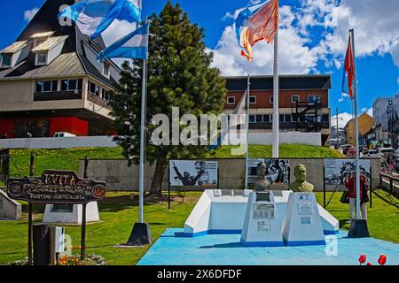 Eine Büste zum Gedenken an Eva Peron (Evita) vor dem Parlamentsgebäude in Ushuaia. Die Stadt ist von schneebedeckten Bergen und Wasserstraßen umgeben. Stockfoto