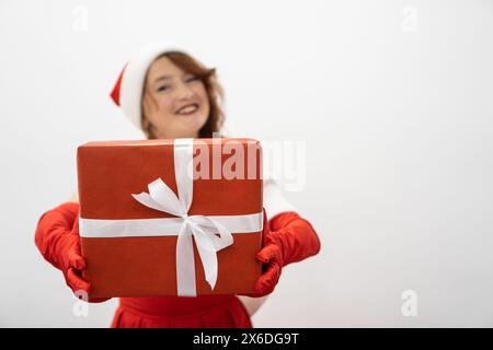 Eine lächelnde Frau in Rot mit einem wunderschön verzierten Geschenk in den Händen sorgt für festliche Stimmung für das neue Jahr und Tränen. Winter-Geschenkferien Stockfoto
