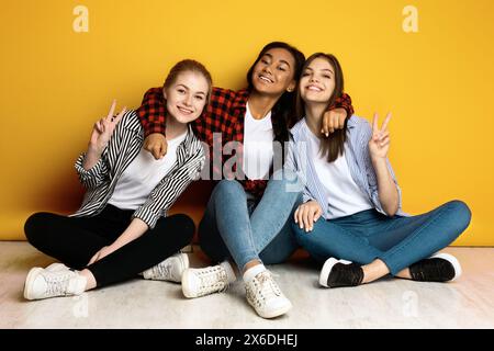 Drei Mädchen sitzen auf dem Boden und posieren für ein Foto Stockfoto