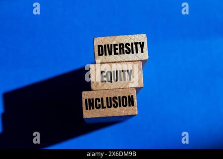 Wörter für Vielfalt, Gerechtigkeit und Einbeziehung auf Holzblock mit blauem Hintergrund. Symbol für konzeptionelle Vielfalt, Gerechtigkeit und Einbeziehung. Kopierbereich für Stockfoto