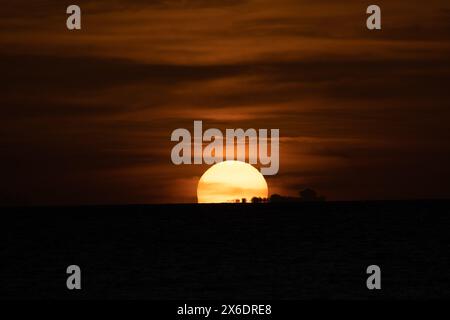Eine faszinierende Nahaufnahme des Sonnenuntergangs über dem Horizont in Martinique, die einen warmen goldenen Glanz über Himmel und Meer ausstrahlt. Dieser atemberaubende Sonnenuntergang capt Stockfoto