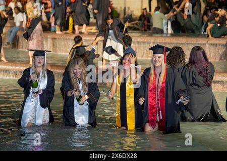 Austin Texas USA, 11. Mai 2024: Die Absolventen der New University of Texas at Austin waten und planschen im Littlefield Fountain, unmittelbar nach der Zeremonie, die in der Nähe des Fußballstadions der Schule stattfand. Der feierliche Dunk ist eine langjährige Campus-Tradition. ©Bob Daemmrich Stockfoto