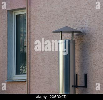 Metalllüftungsrohre an der Außenwand eines beigefarbenen Industriegebäudes vor Hintergrund. Stockfoto