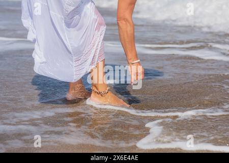 Frauenfüße, die von Meereswellen gewaschen werden Stockfoto