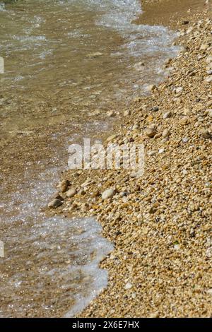 Kleine Steine am Strand mit einigen Wellen Wasser Stockfoto