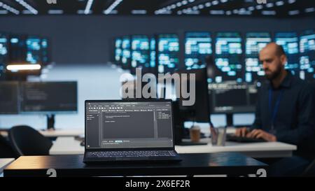 Konzentrieren Sie sich auf Laptops, die von Programmierern verwendet werden, die Code im unscharfen Hintergrund für Rechenzentrumsserver ausführen, Fehlerbehebungsgeräte. Nahaufnahme der Codezeilen auf dem Notebook-Bildschirm im Server-Hub Stockfoto