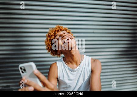 afroamerikanischer Teenager, der mit dem Telefon lächelt. Stockfoto