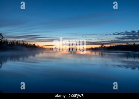 Die Sonne geht im Norden von Minnesota nahe Duluth über einer wunderschönen Seeszene auf, während Dampf aus dem ruhigen Wasser steigt Stockfoto