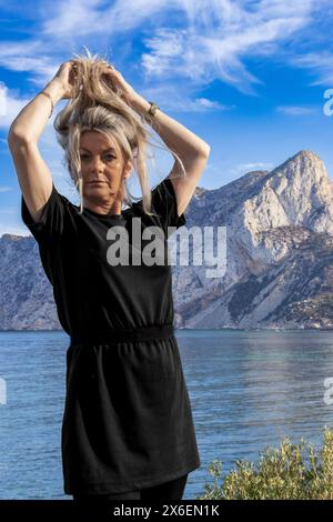 Dieses Porträt zeigt eine wunderschöne Frau in der spanischen Stadt Calpe, deren Gesicht von der mediterranen Sonne beleuchtet wird, mit dem ikonischen Ifach Rock Stockfoto