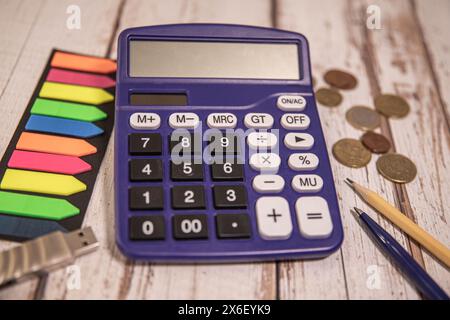 Geschäftsmann mit Taschenrechner und Modellhaus mit Solarmodul auf Holztisch. Stockfoto