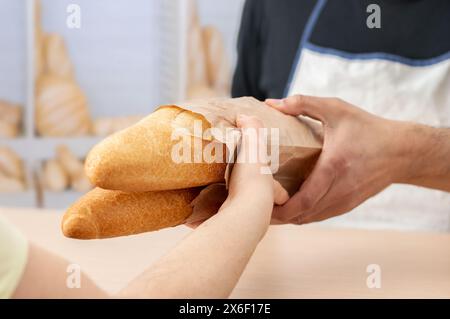 Kurze Aufnahme einer Frau, die frisch zubereitete Baguettes oder Brot im Café kauft Stockfoto