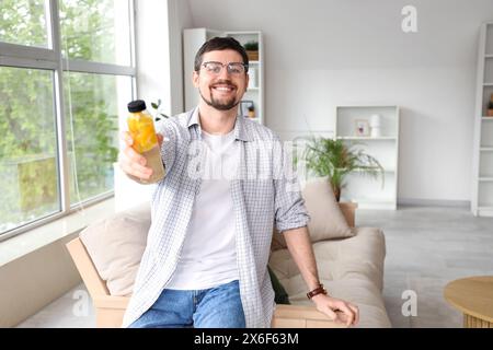 Junger Mann mit einer Flasche Zitronenwasser zu Hause Stockfoto