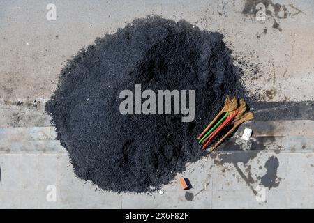 Ein Haufen Asphalt, der auf der Straße liegt, zusammen mit Besen Stockfoto