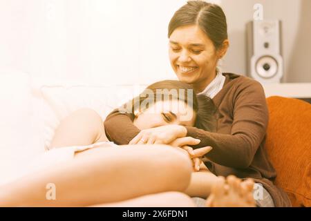 Die mütterliche Liebe, dargestellt als ältere Frau, und ihr jüngeres Pendant teilen einen herzlichen Moment zu Hause Stockfoto