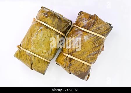 Khao tom Mat ist ein beliebtes süßes thailändisches Dessert aus Klebreis, reifer Banane, Kokosmilch, gewickelt und in Bananenblättern gedämpft. Stockfoto