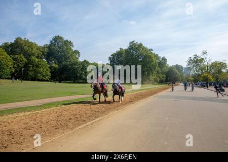 Hyde Park London während der Hitzewelle im September 2023, Radfahren und kleine Kinder reiten auf dem Sandweg, England, Großbritannien Stockfoto