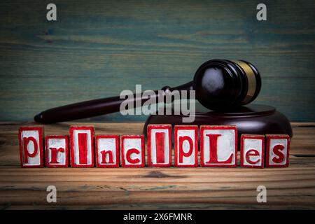 GRUNDSÄTZE. Rote Buchstaben und richterlicher Hammer auf hölzernem Hintergrund. Recht und Justizkonzept. Stockfoto