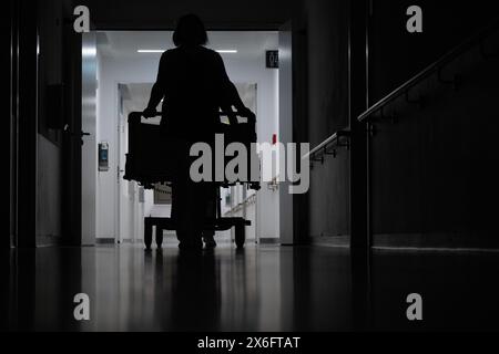 Stuttgart, Deutschland. Mai 2024. Eine Krankenschwester schiebt ein Patientenbett durch den Flur einer Krankenhausstation. Quelle: Marijan Murat/dpa/Alamy Live News Stockfoto