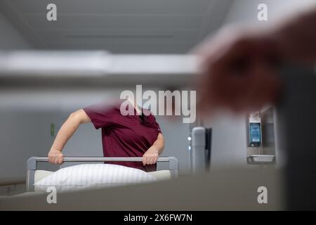 Stuttgart, Deutschland. Mai 2024. Eine Krankenschwester schiebt ein Patientenbett durch den Flur einer Krankenhausstation. Quelle: Marijan Murat/dpa/Alamy Live News Stockfoto