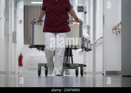 Stuttgart, Deutschland. Mai 2024. Eine Krankenschwester schiebt ein Patientenbett durch den Flur einer Krankenhausstation. Quelle: Marijan Murat/dpa/Alamy Live News Stockfoto