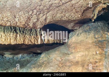 Eine Höhle mit einer braunen Wand und einem kleinen Loch darin. Die Höhle ist dunkel und die Wände sind rau. Stockfoto