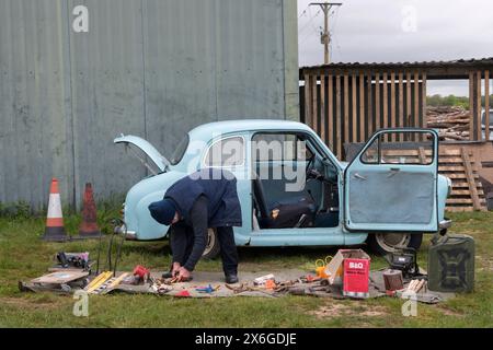 Poverty Car Boot Sale UK.2020s. Ein alter Mann packt seine Sachen am Ende eines Autoschuhverkaufs ein. Er steckt Sachen, die noch nicht verkauft wurden, in sein britisches Austin A35-Auto. Sonntagmorgen bei Strawberry Fields Car Boot Event in Lymington, Hampshire England 2024 HOMER SYKES Stockfoto