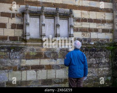 Senior man liest die Namen auf einer Gedenkstätte für den 1. Weltkrieg, St. Peters Church, Northampton, Großbritannien Stockfoto