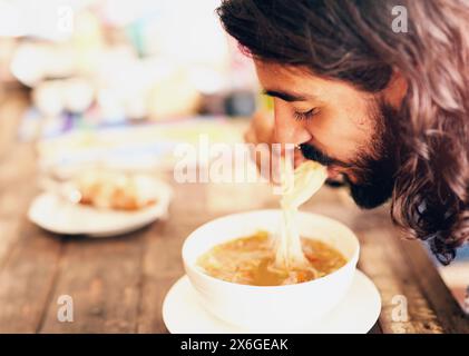 Chinesisches Essen, Mann und Essen Nudeln im Restaurant für Mittag-, Abendessen oder gesunde Ernährung in der Schüssel. Ramen, Suppe und hungrige Person mit Stäbchen zum Essen Stockfoto