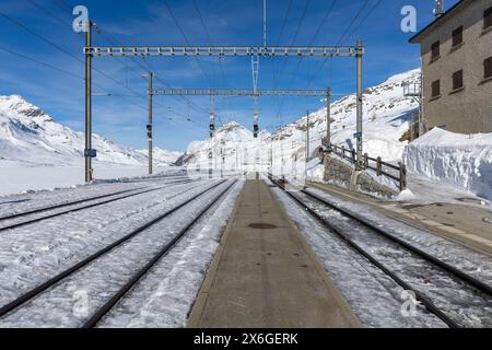 Bahnhof am Berninapass in der Schweiz. Vorderansicht vom Bahnsteig und Gleise aus dem Schnee. Niemand drinnen Stockfoto