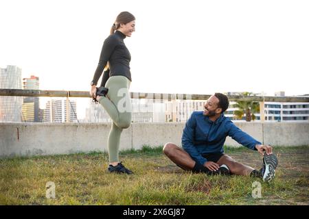 Ein junges, lächelndes, sportliches Paar, das sich dehnt. Stockfoto