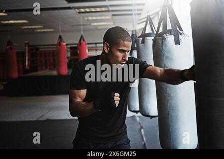 Hit, Boxsack und Mann im Boxstudio für Workout, Challenge oder Wettkampftraining. Kraft, Muskeln und starker Champion Boxer im Training mit Stockfoto