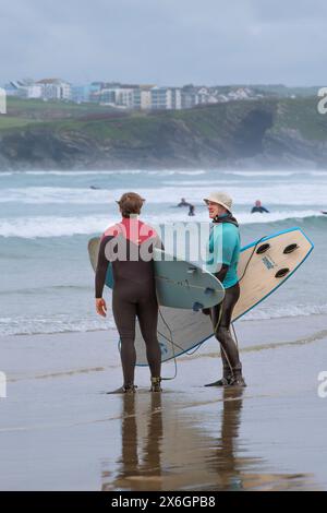 Ein Surflehrer der Escape Surf School unterhält sich mit einem anderen Surfer am Towan Beach in Newquay in Cornwall, Großbritannien. Stockfoto