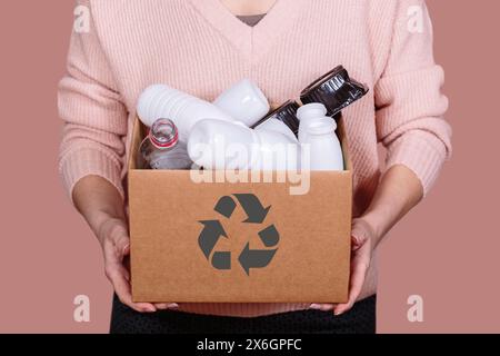 Frau hält Pappkarton mit Plastikabfällen Stockfoto