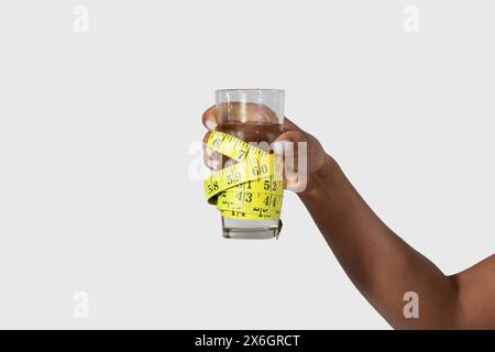 Frau, die Maßband an einem Glas Wasser hält, abgeschnitten Stockfoto