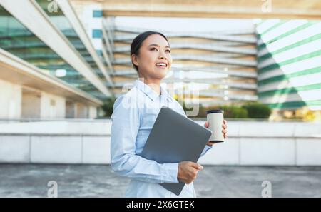 Junge asiatische Geschäftsfrau mit Laptop und Tasse Kaffee Stockfoto