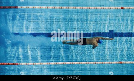 Außenansicht männlicher Schwimmer, der im Swimmingpool schwimmt. Profi-Athletentraining für die Meisterschaft mit Front Crawl und Freestyle-Technik. Top-Down-Ansicht. Stockfoto