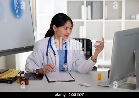 Asiatische Ärztin, die Medikamentenflasche in der Klinik analysiert Stockfoto