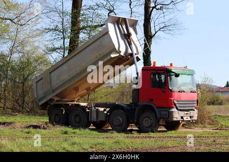 Geparkte Lkw-Dreiwege-Kipper mit offenem Oberteil zum Transport von losem Material, das auf der örtlichen Baustelle zurückgelassen wird Stockfoto