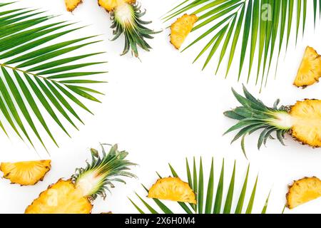 Tropischer Rahmen mit geschnittenen Ananas- und Palmenblättern auf weißem Hintergrund. Flache Lage, Draufsicht. Stockfoto