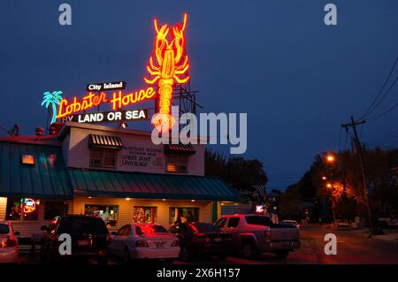 Ein großes Neonlicht-Schild wird nachts über einem Fischrestaurant und Café auf City Island, New York, beleuchtet Stockfoto