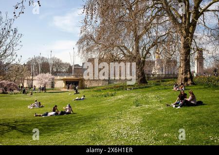 Die Leute sitzen im Park vor dem Buckingham Palace und dem Coffee Kiosk. The Horseshoe Kiosk, The Royal Parks, Westminster, Großbritannien. Architec Stockfoto