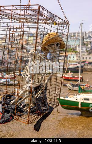 Skelett in einem Käfig, der über dem Hafen hängt, Brixham, Devon, England, Großbritannien Stockfoto