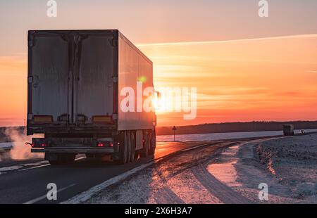Semi-Truck fährt auf einer verschneiten Autobahn bei Sonnenuntergang im Winter Stockfoto