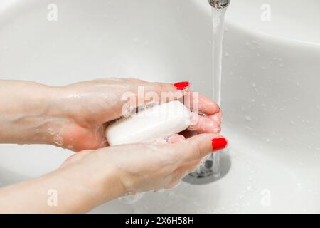 Frau wäscht sich die Hände mit Seife im Badezimmer. Handseife. Die Hand der Frau, die Seife hält Stockfoto