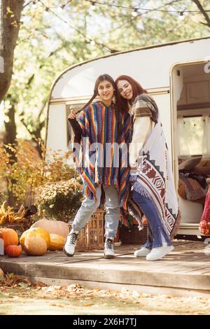 Zwei angesagte Mädchen zeigen ihre Hippie-inspirierten Outfits im Trailer-Setting. Stockfoto