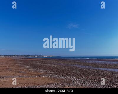 Blick nach Norden in Richtung Arbroath in der Entfernung von Elliot Beach, mit seinen Kieselbänken, die an einem klaren Tag im Mai bei High Tide freigelegt sind. Stockfoto