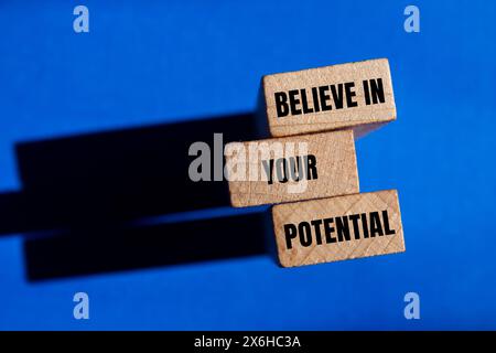 Glauben Sie an Ihre potenziellen Worte auf Holzblöcken mit blauem Hintergrund. Glauben Sie konzeptionell an Ihr potenzielles Symbol. Kopierbereich. Stockfoto