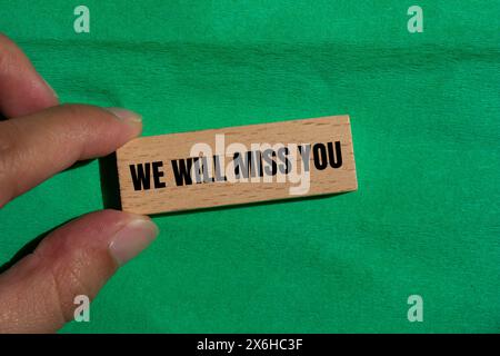 Wir werden Sie vermissen, geschrieben auf Holzblock mit grünem Hintergrund. Konzeptionell werden wir dich vermissen Symbol. Kopierbereich. Stockfoto